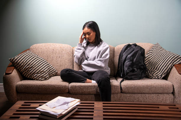 a university student of asian heritage experiencing financial or emotional stress at home in her apartment. - sad asian woman stock pictures, royalty-free photos & images