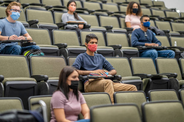 universitaire studenten die maskers in een lezingszaal dragen - universiteit stockfoto's en -beelden