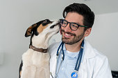 Very happy veterinarian getting a kiss from a dog