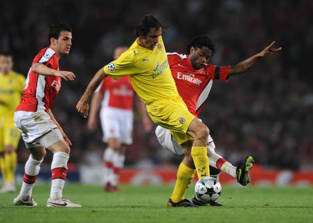 Villarreal's Robert Pires is fouled by Arsenal's Alexandre Song Billong as Arsenal's Cesc Fabregas looks on