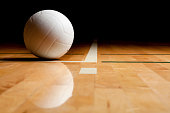 A volleyball and reflection on a wooden floor