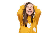 Waist up studio portrait of an adorable young girl laughing with excitement, head in hands and closed eyes, isolated on white backgroud. Human emotions and facial expressions concept.
