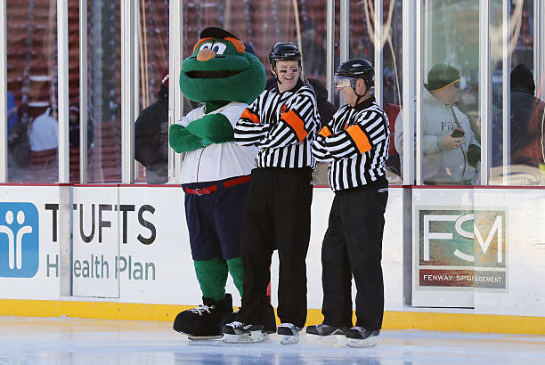 Wally the Green Monster jokes around with the referees before a Frozen Fenway NCAA Men's Division 1 hockey game between the Boston University...