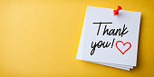 White Sticky Note With Thank You And Red Push Pin On Yellow Background