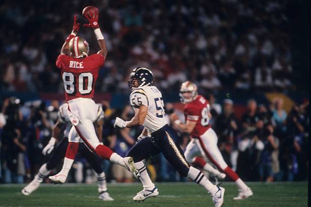 Wide receiver Jerry Rice of the San Francisco 49ers catches a pass behind linebacker Junior Seau of the San Diego Chargers in Super Bowl XXIX at Joe...