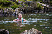 Wild swimming woman in clear mountain stream Lake District Cumbria