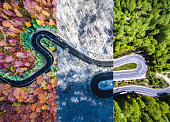 Winding road in the forest. Autumn, summer and winter time colage. Top down aerial view from a drone.