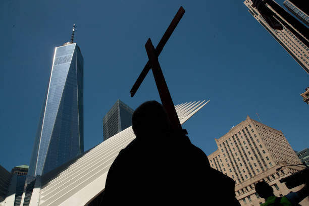 With firefighter John Barlett carrying the cross, the Way of the Cross procession makes its way through Lower Manhattan on Good Friday, April 14,...