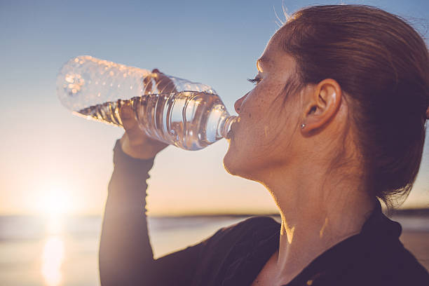 woman drinking water seaside. - drink water stock pictures, royalty-free photos & images