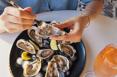Woman eating fresh oysters with lemon close-up.