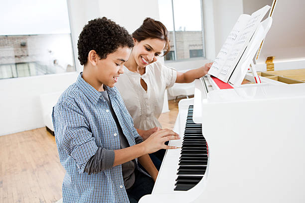 Woman giving piano lesson to boy