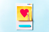 Woman hand holding a social media love influencer concept with red heart symbol on paper card and blue background. Digital marketing concept.
