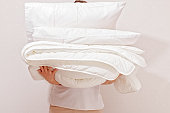 Woman holding a pile of bedding for sleeping. Household