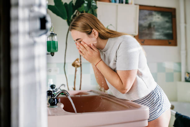 woman in bathroom washing face - 洗顔 ストックフォトと画像