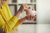 Woman inserts a coin into a piggy bank