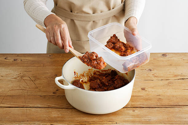 woman spooning meat into tupperware - food containers stock pictures, royalty-free photos & images