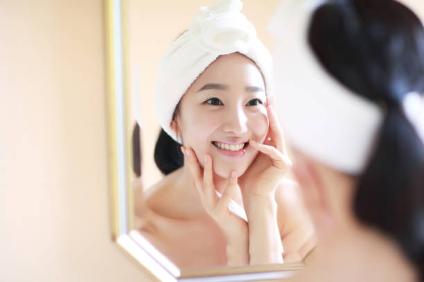 woman touching face in mirror - skin treatment stock pictures, royalty-free photos & images