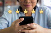 Woman using cell phone with 5 gold star customer satisfaction graphic