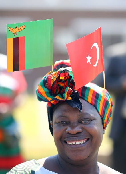 A woman wearing a headband carries Flags of Turkey and Zambia over her head during an official welcoming ceremony by Zambian President Edgar Lungu...