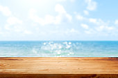 Wooden table top on blurred summer blue sea and sky background. Copy space for your display or montage product design.