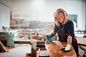 Woodworker using a hand sander to sand down a wooden surface