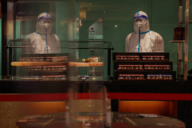 Worker in a hazmat suit works in a hotel restaurant buffet section, which is part of the closed-loop Winter Olympics Accommodation Allocation...