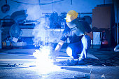 Worker while doing a welding with arc welder with smoke