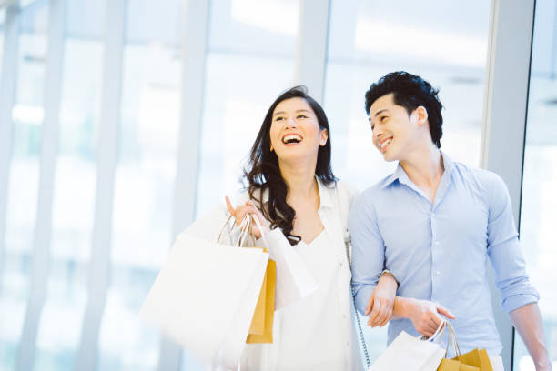 young asian couple enjoying shopping in the mall - asian couple in a mall stock pictures, royalty-free photos & images