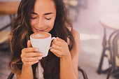 Young beautiful happy woman enjoying cappuccino in a cafe