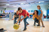Young boy bowling with family