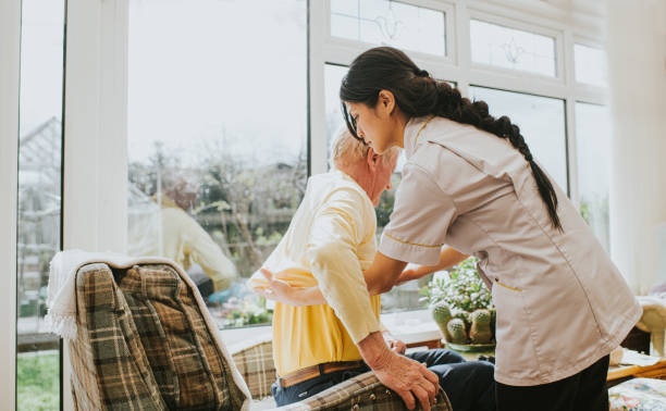 young care assistant helps an elderly gent put on his jumper - caregivers stock pictures, royalty-free photos & images