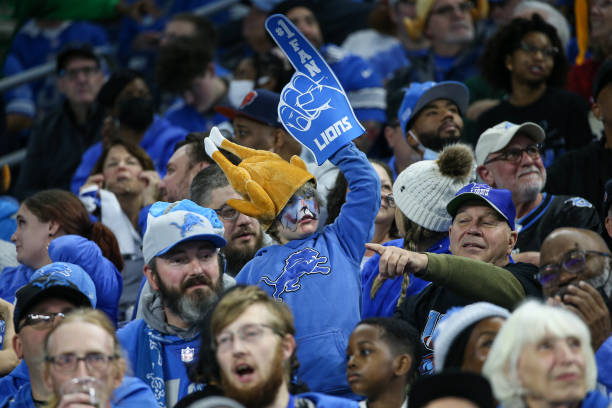 Young Detroit fan wears a turkey-themed hat and holds up a large foam finger during a regular season Thanksgiving Day NFL football game between the...