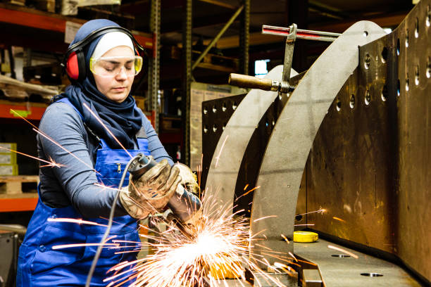 young female trainee works with a grinder in a workshop, flying sparks - student workers stock pictures, royalty-free photos & images