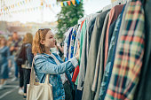 Young girl choosing clothes in a second hand market in summer, zero waste concept