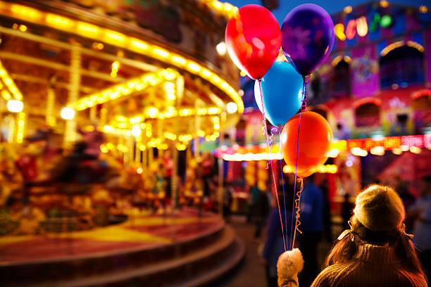 Young girl holding balloons at the fairground