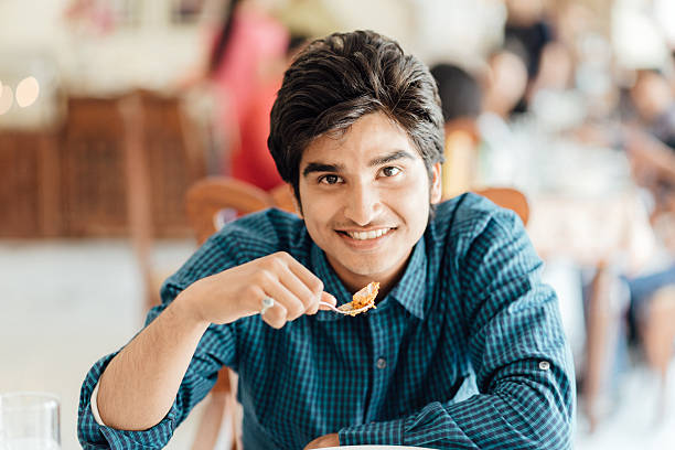 young indian male eating in restaurant - asian man eating stock pictures, royalty-free photos & images