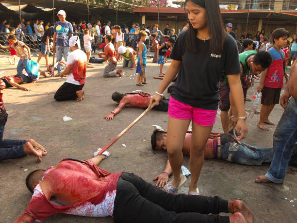 Young lady seen serving as an executioner to a flagellate crawling on the pavement during Good Friday. Devout catholics in the deeply religious...