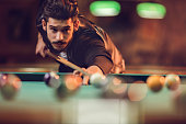 Young man playing billiard in a pool hall.