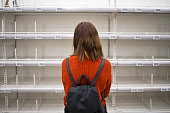Young woman standing in front of empty shelf in a supermarket