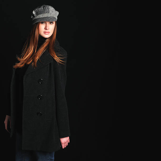 young woman wearing wool peacoat and hat, isolated on black - peacoat stock pictures, royalty-free photos & images