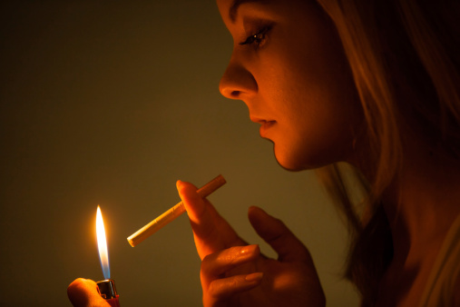 Young woman with lighter lighting up cigarette. Girl smoking.