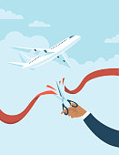 Human hand cuts red ribbon to start airlines flights again after coronavirus COVID-19 quarantine.
