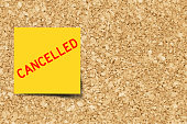 Yellow note with word cancelled on cork board background  with copy space (Vector)