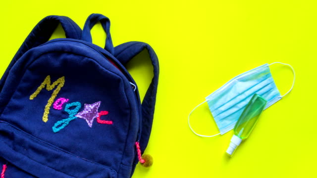 Backpack with school supplies and sanitizer and medical protective mask stop motion animation. Back to school after quarantine concept.