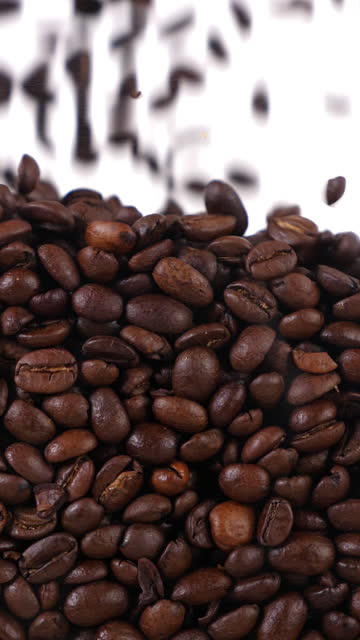 coffee beans fall in slow motion and cover the whole screen, vertical video