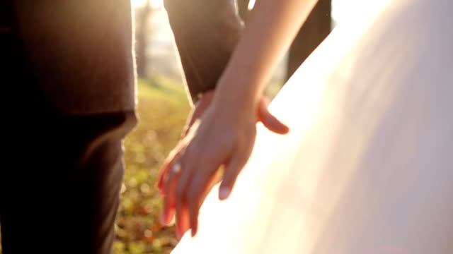 newly married couple walk together holding hands shot in slow motion  close up
